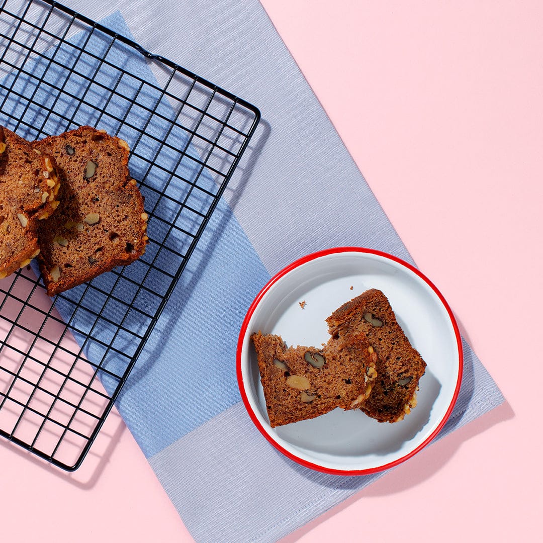 Top view of Banana and Walnut Loaf showing walnuts pieces on pink background.