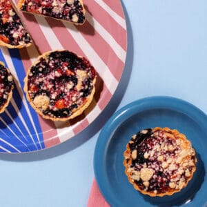 Top view of Blueberry and Lemon Muffin Tart with lemon sponge and blueberries on blue background.