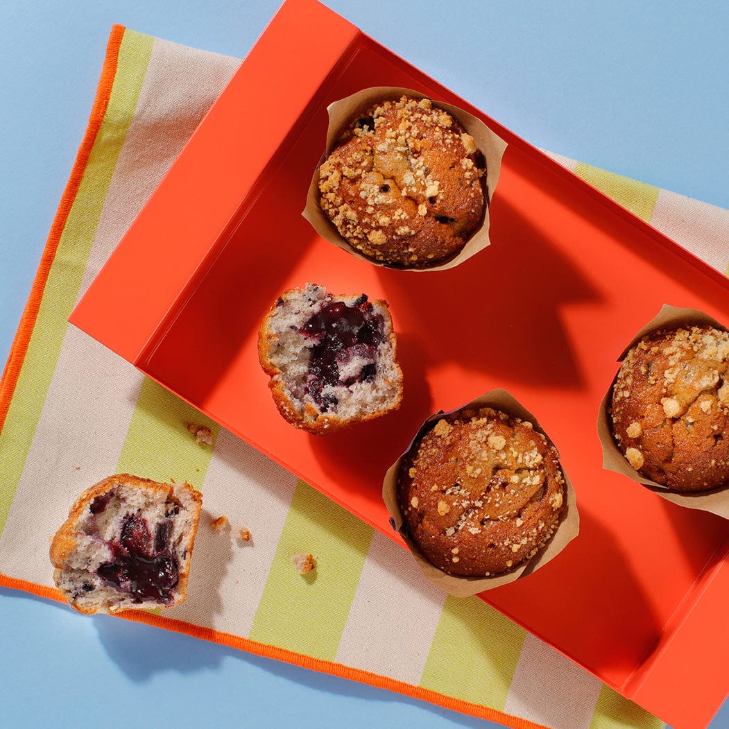 An overhead view of our scrumptious Blueberry Muffins in a presentation box. Two of the muffins have been half eaten.