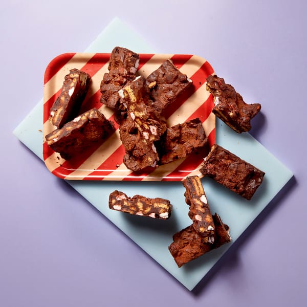 A whole tray of Cake Club Rocky Road on a red and white striped plate on a purple background.