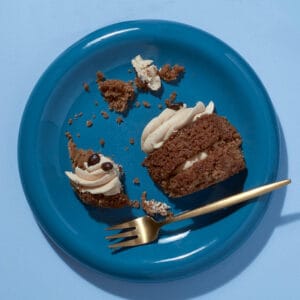 Overhead view of a small latte-flavored cupcake with crumbs scattered around it, from CakeClubs' - the Little Latte.