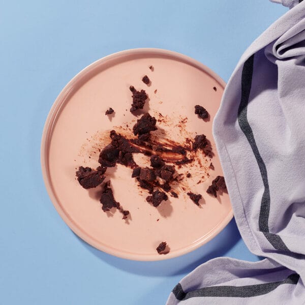 Empty plate with crumbs from Choc Chunk Brownie – gluten-free chocolate brownie.