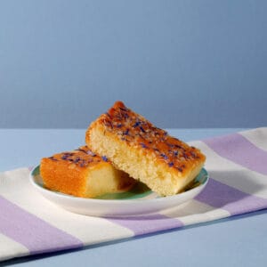 Lemon Drizzle Cake slices on a plate with purple striped napkin | Cake Club.