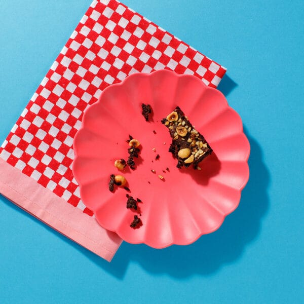 An overhead view of a plate containing a half eaten Praline Melt Brownie and some crumbs.
