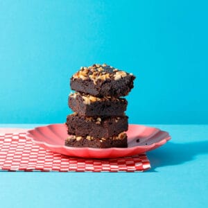 Three slices of our Praline Melt Brownie stacked on top of each other on a plate.