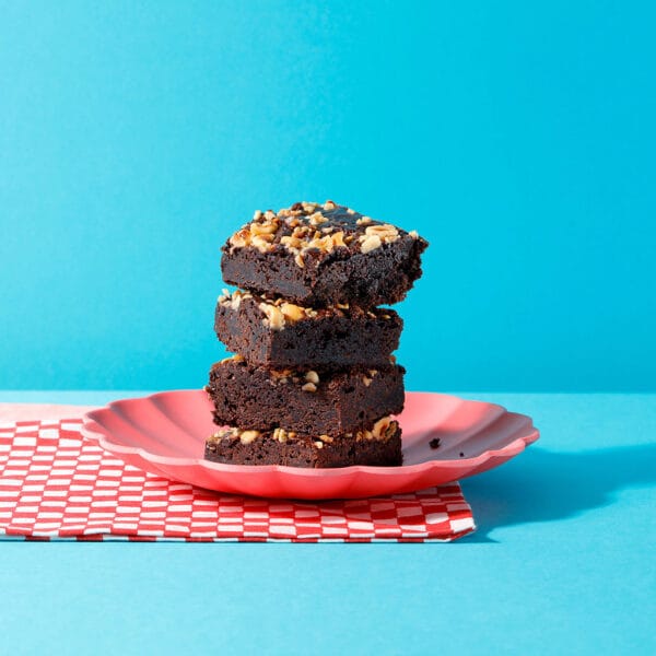 Three slices of our Praline Melt Brownie stacked on top of each other on a plate.