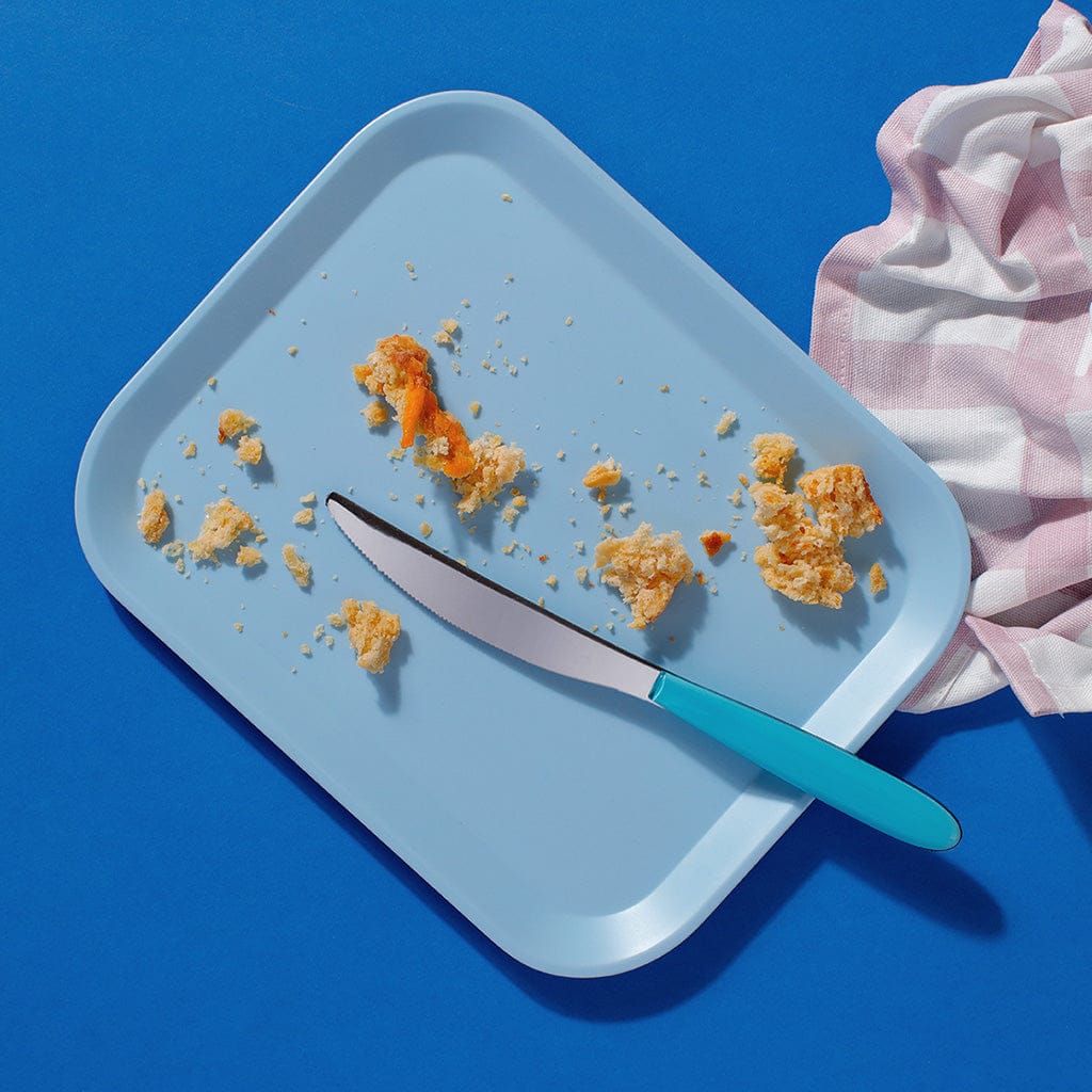 Half-eaten Big Cheese scone on blue tray with crumbs and butter knife for café display.