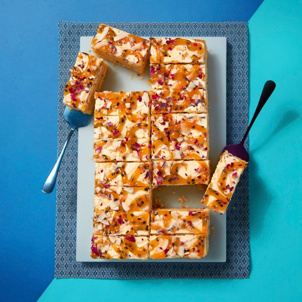 A full tray of Passionfruit and Coconut Traycake by Cake Club on a blue patterned cloth and background.