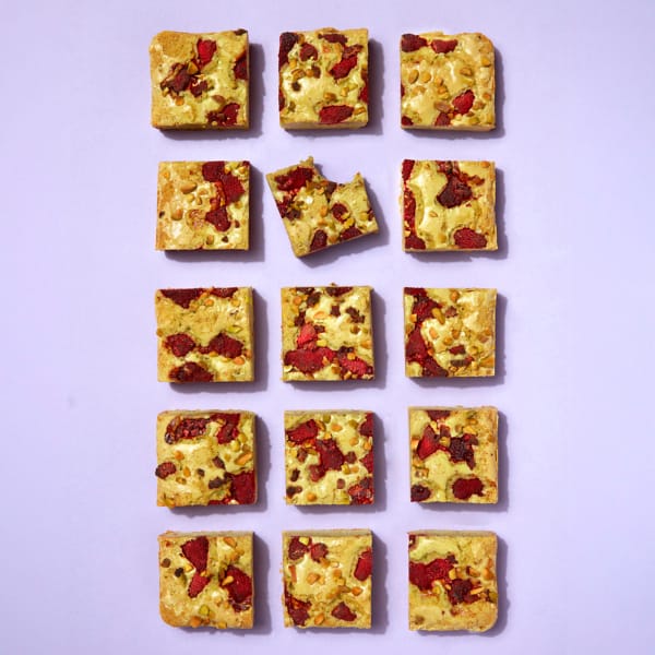 A full tray of Cake Club Pistachio and Raspberry Blondie on a purple background.
