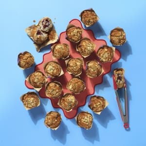 A whole tray of Cake Club blueberry muffins on a wavy orange mat on a light blue background.