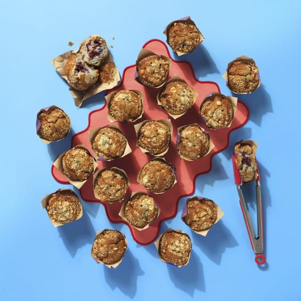 A whole tray of Cake Club blueberry muffins on a wavy orange mat on a light blue background.