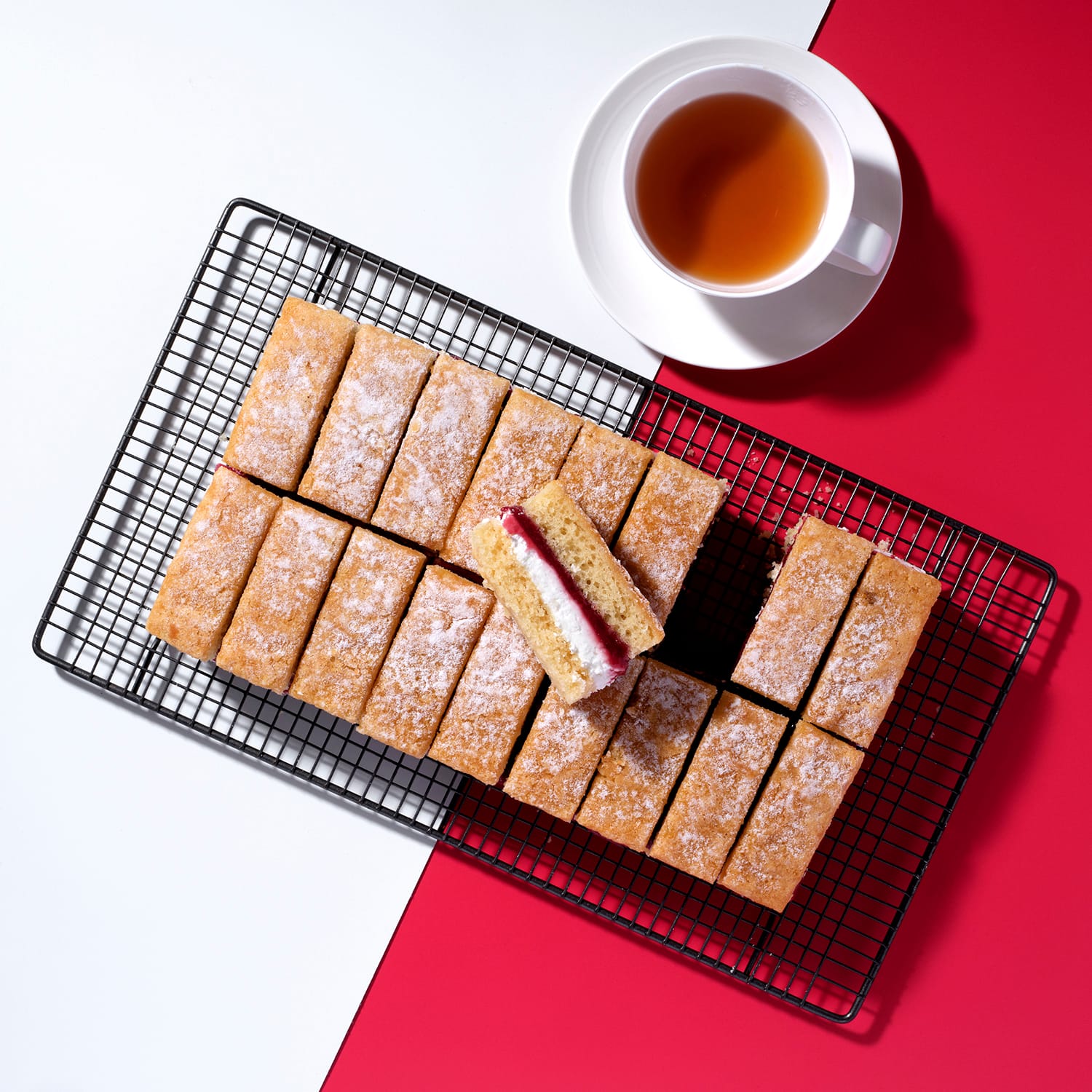Pre-cut Victoria Sponge Traycake on cooling rack with cup of tea, Cake Club.