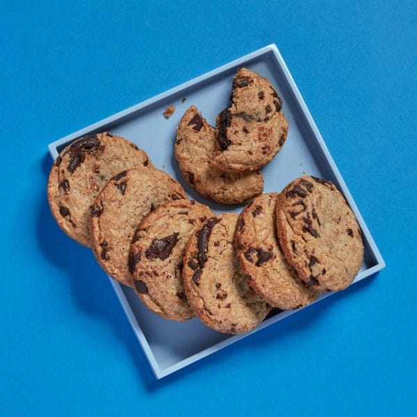 Loaded Chocolate Chip Cookies stacked on a blue surface.