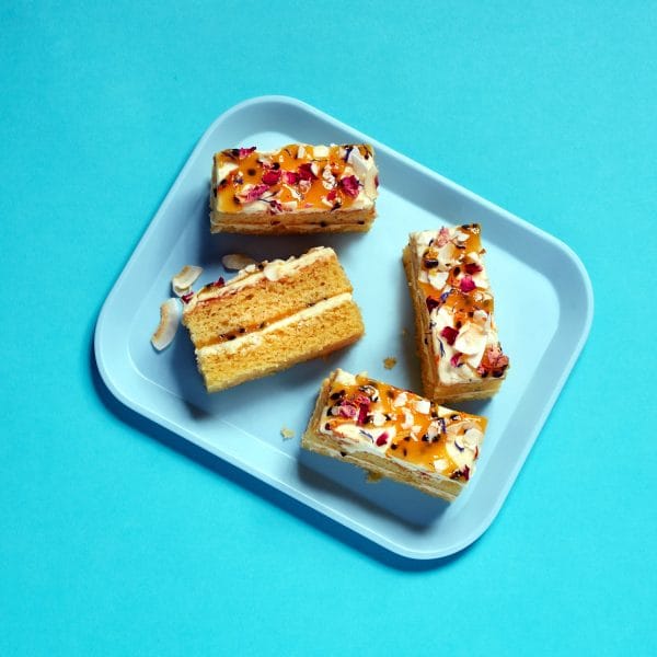 Passionfruit and Coconut Traycake portions stacked next to each other on a blue tray.