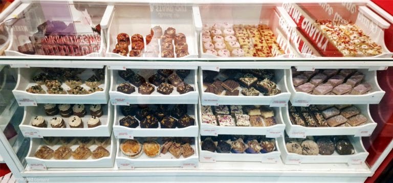 Cake display cabinet filled with traybakes, brownies, blondies, muffins and pastries, showing variety and quality from a professional cake supplier.