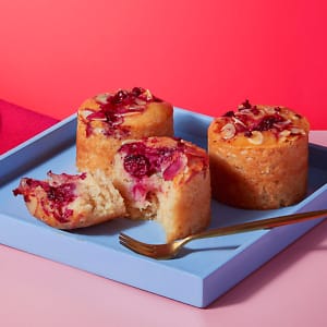 Mini Cherry Bakewell sponges on a blue tray with a pink table background.